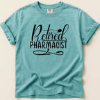 Teal t-shirt with "Retired Pharmacist" text and pill graphic.