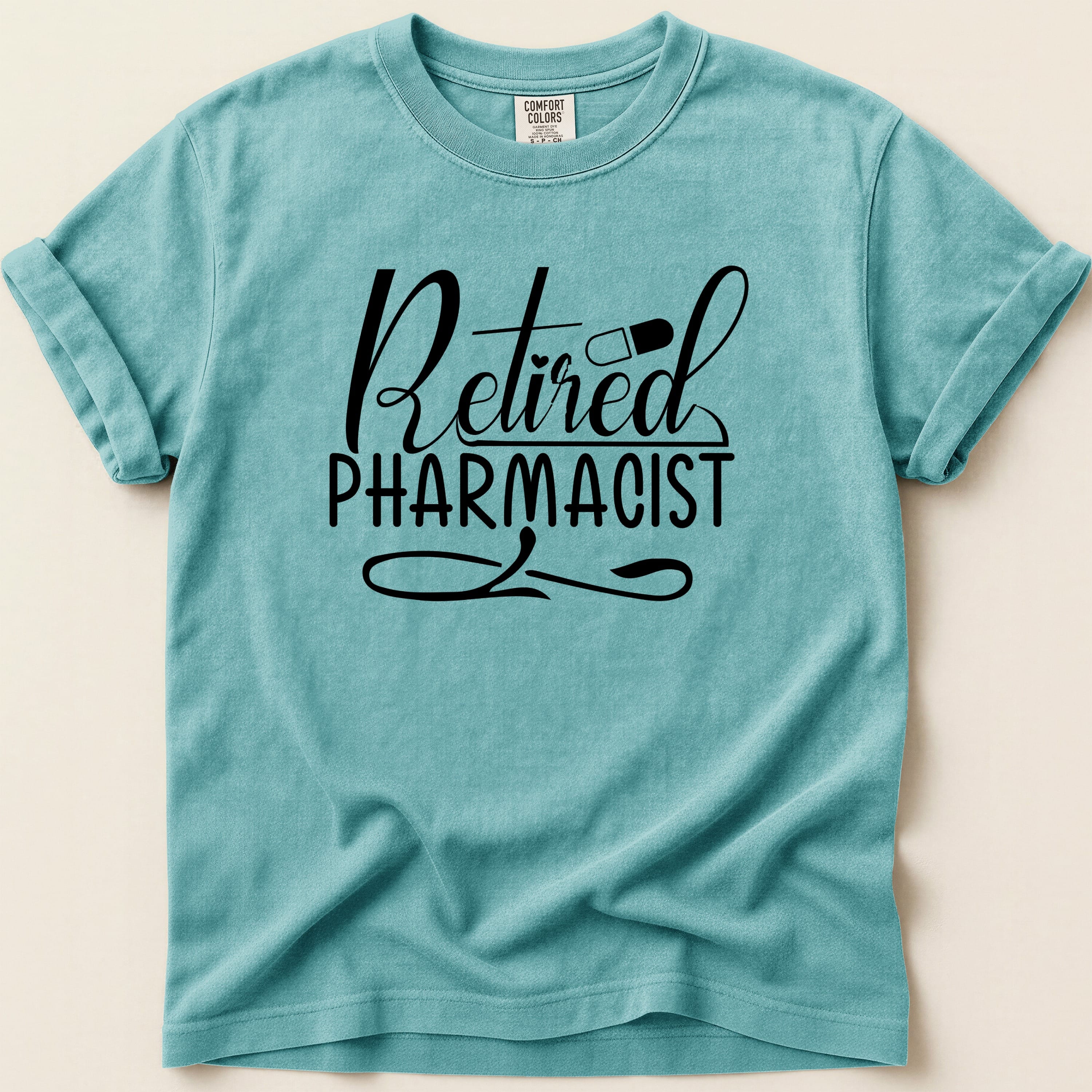 Teal t-shirt with "Retired Pharmacist" text and pill graphic.