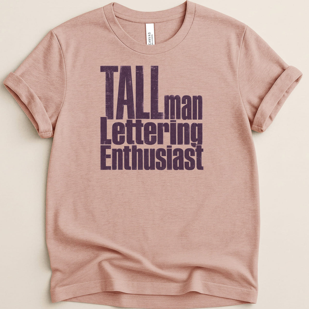 Pink t-shirt with "TALLman Lettering Enthusiast" in distressed purple text.
