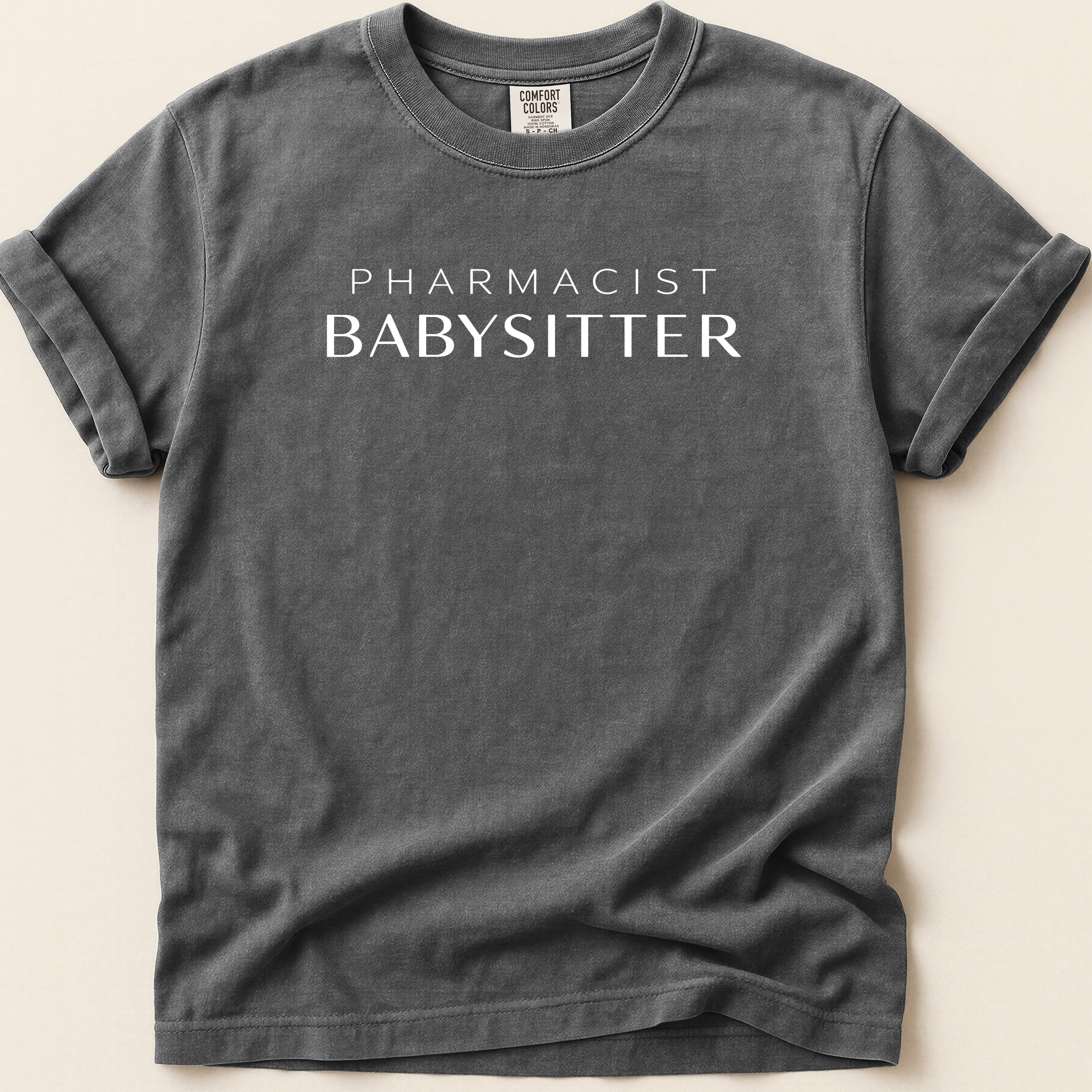 Dark gray t-shirt with white text "PHARMACIST BABYSITTER".