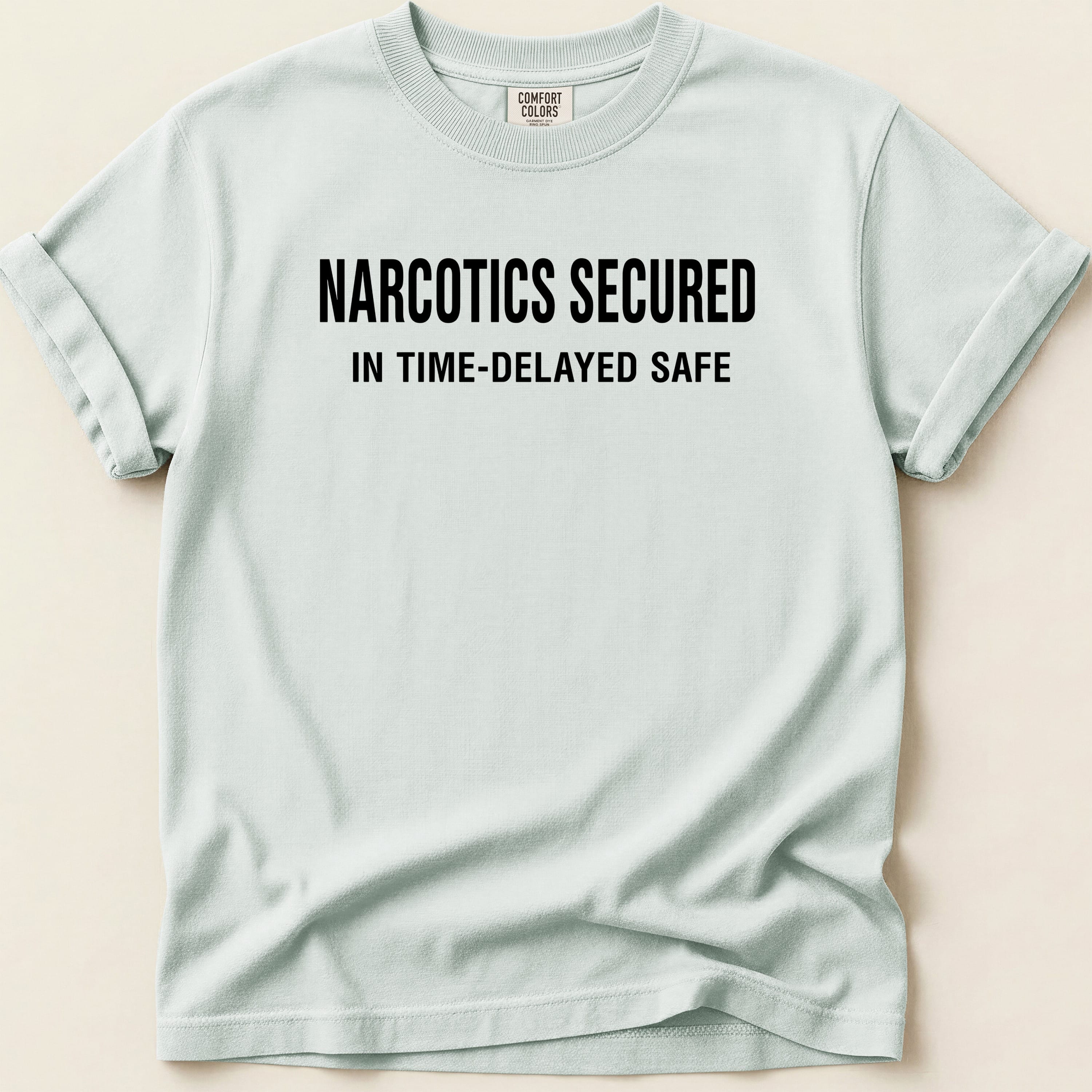 Light blue t-shirt with black text "NARCOTICS SECURED IN TIME-DELAYED SAFE".