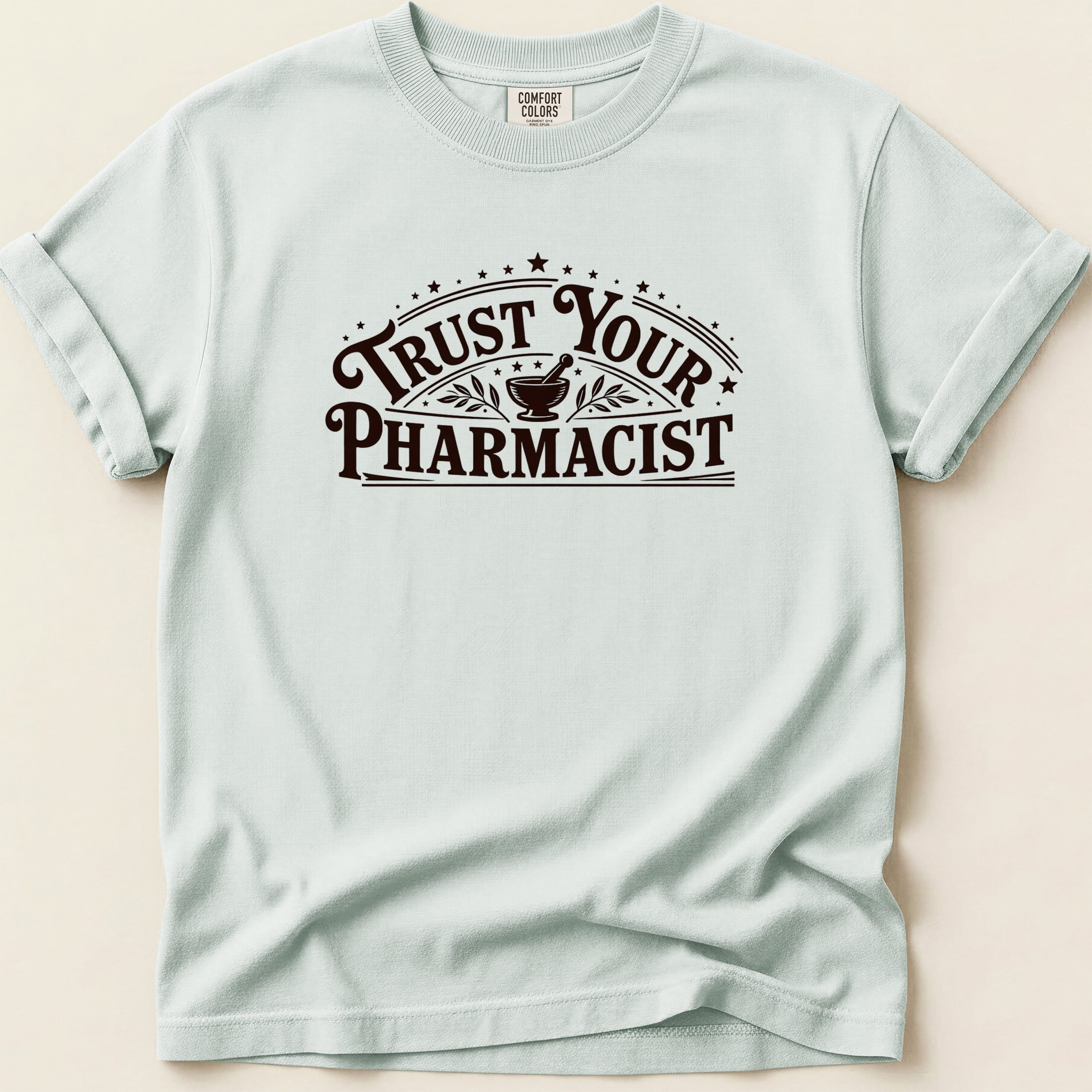Light blue t-shirt with "Trust Your Pharmacist" text and starburst design.