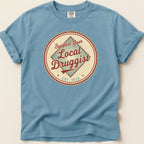 Blue t-shirt with circular "Support Your Local Druggist Est. 1920" graphic.