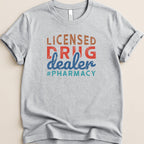 Light gray t-shirt with "Licensed Drug Dealer #Pharmacy" in colorful text.