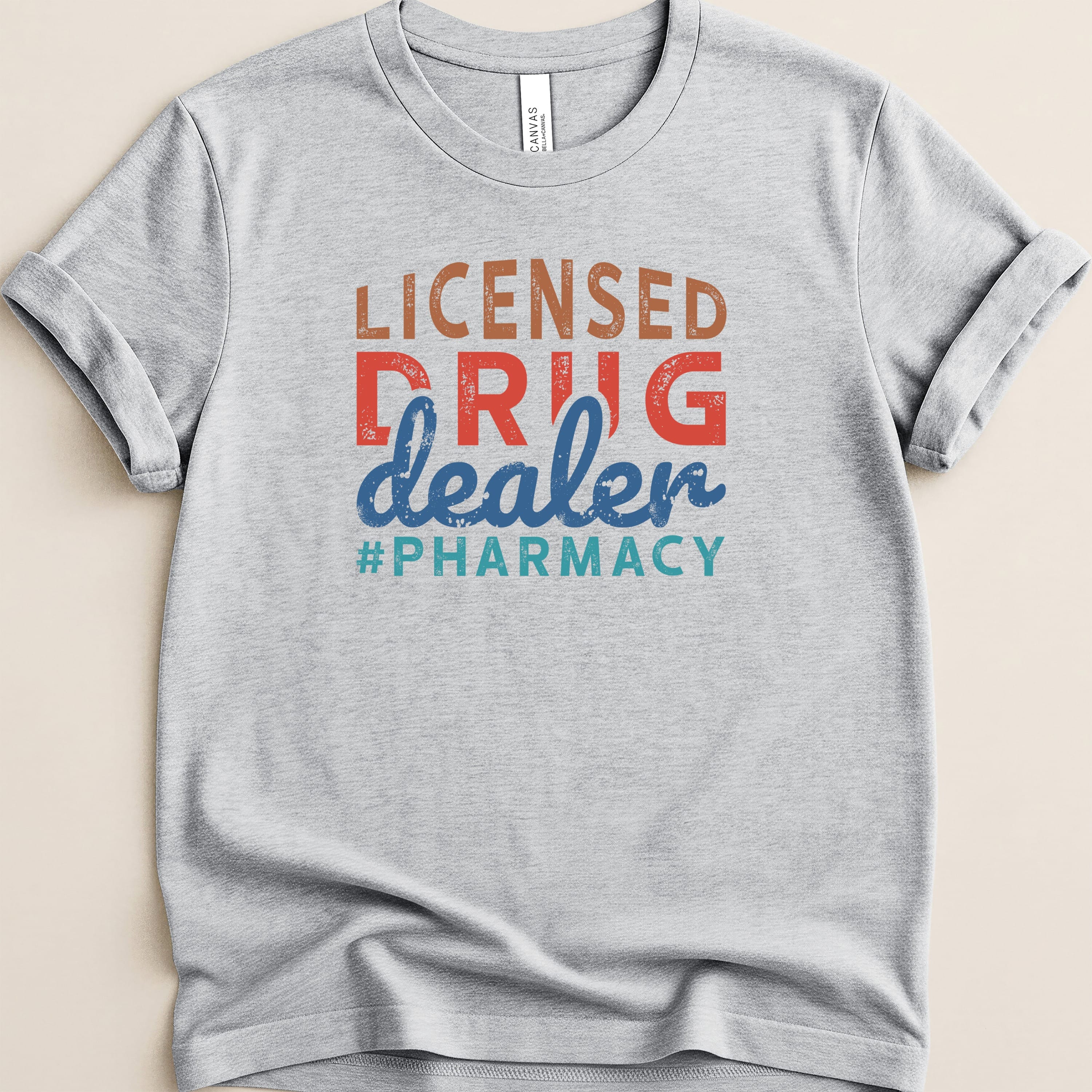 Light gray t-shirt with "Licensed Drug Dealer #Pharmacy" in colorful text.