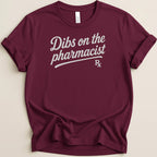 Maroon t-shirt with "Dibs on the pharmacist Rx" graphic in white script.