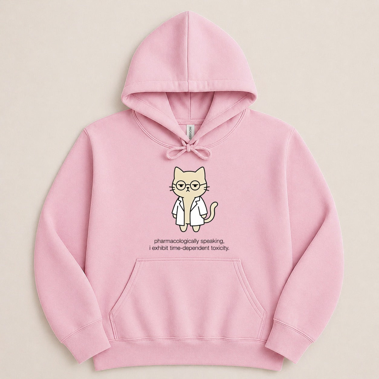 Pink hoodie with cartoon cat wearing glasses and lab coat, text reads "pharmacologically speaking, i exhibit time-dependent toxicity."