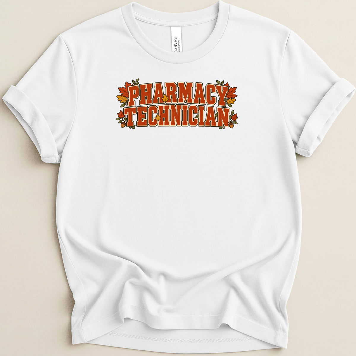 White t-shirt with rolled sleeves displaying the text Pharmacy Technician in orange block letters surrounded by autumn leaves.