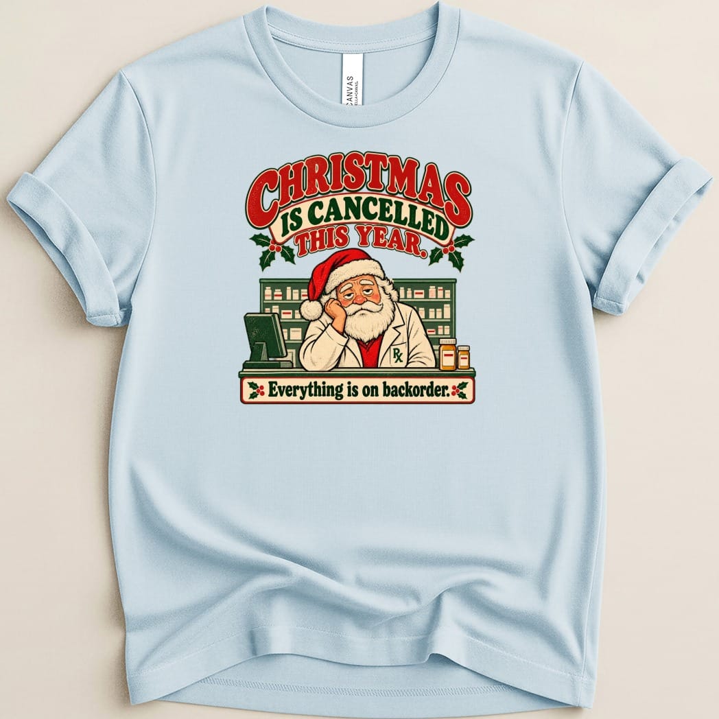 A light blue crewneck t-shirt featuring a graphic of Santa Claus as a pharmacist, with text that reads Christmas is cancelled this year.