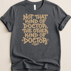 Dark grey t-shirt with tan text reading "Not that kind of doctor, the other kind of 'doctor'."