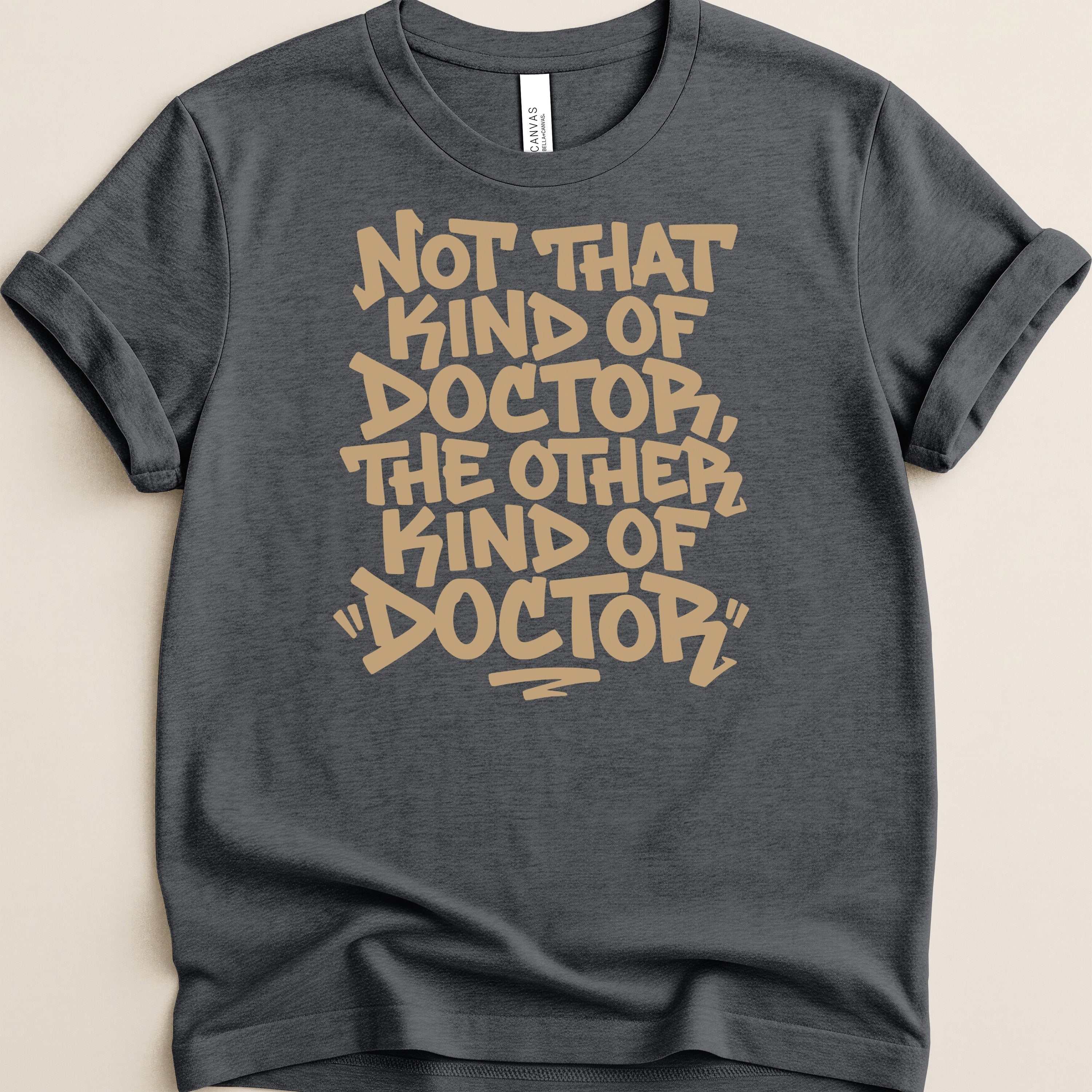 Dark grey t-shirt with tan text reading "Not that kind of doctor, the other kind of 'doctor'."