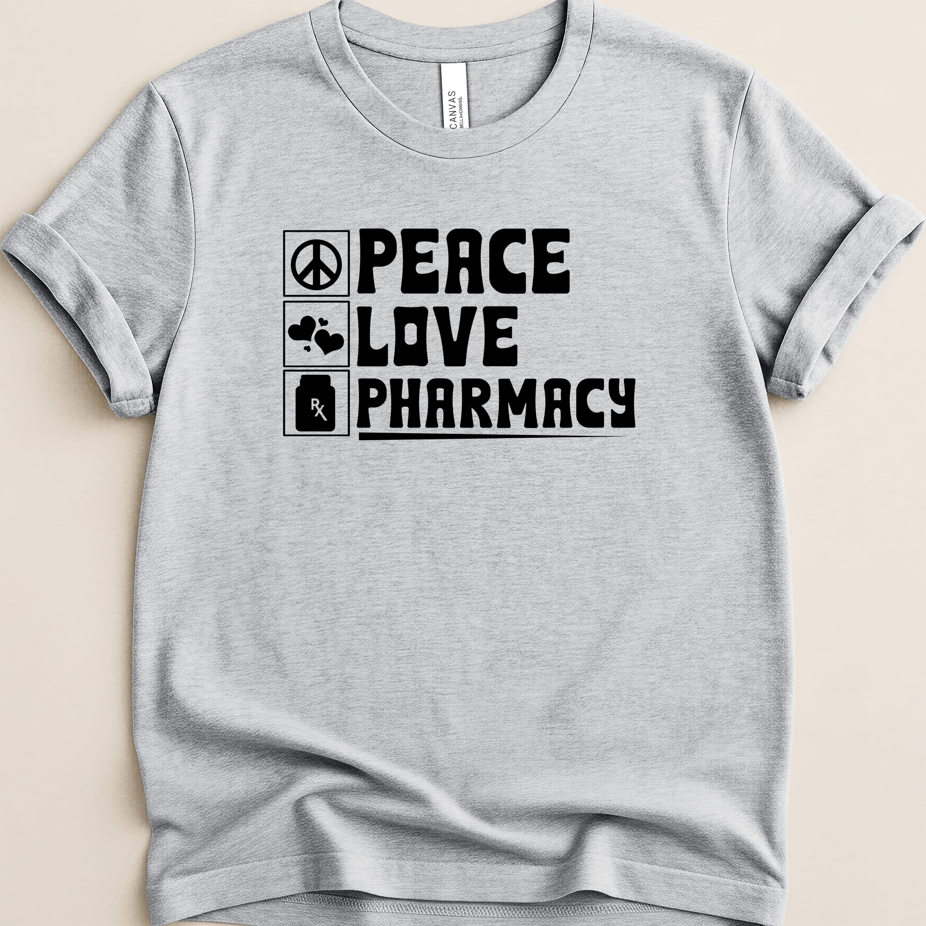 Grey t-shirt with black text: "Peace Love Pharmacy" and icons for heart and prescription.