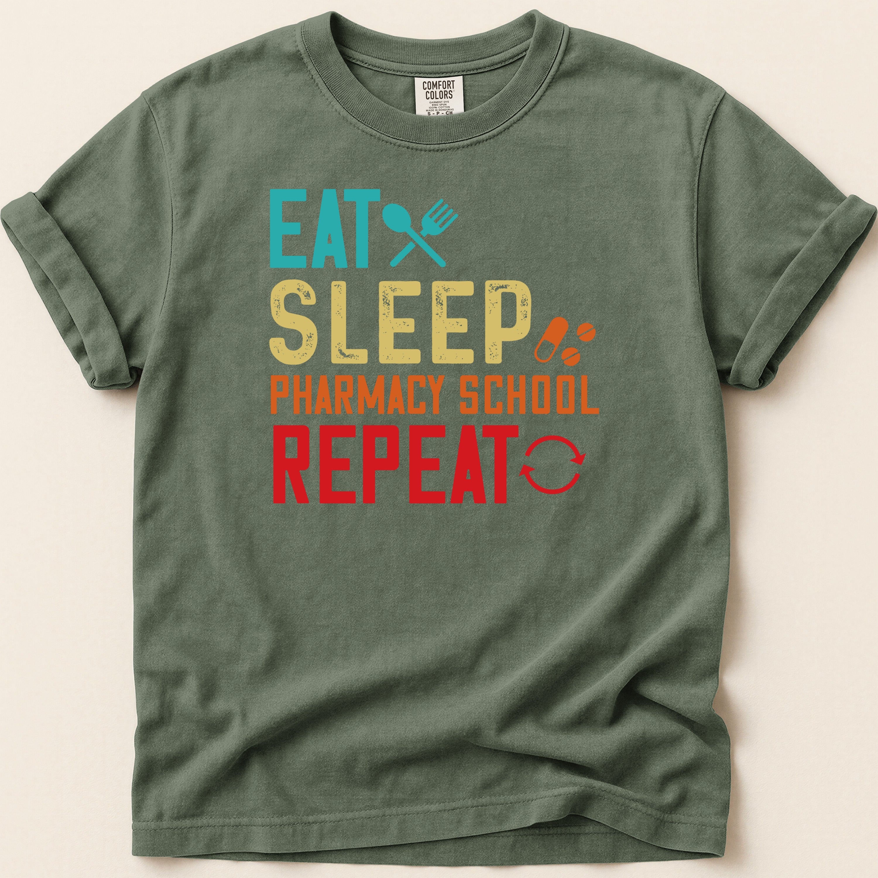 Green t-shirt with "Eat Sleep Pharmacy School Repeat" text.