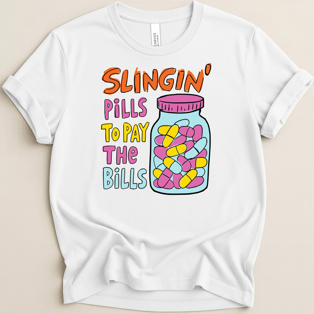 White t-shirt with "Slingin' Pills To Pay The Bills" text and a jar of pills.
