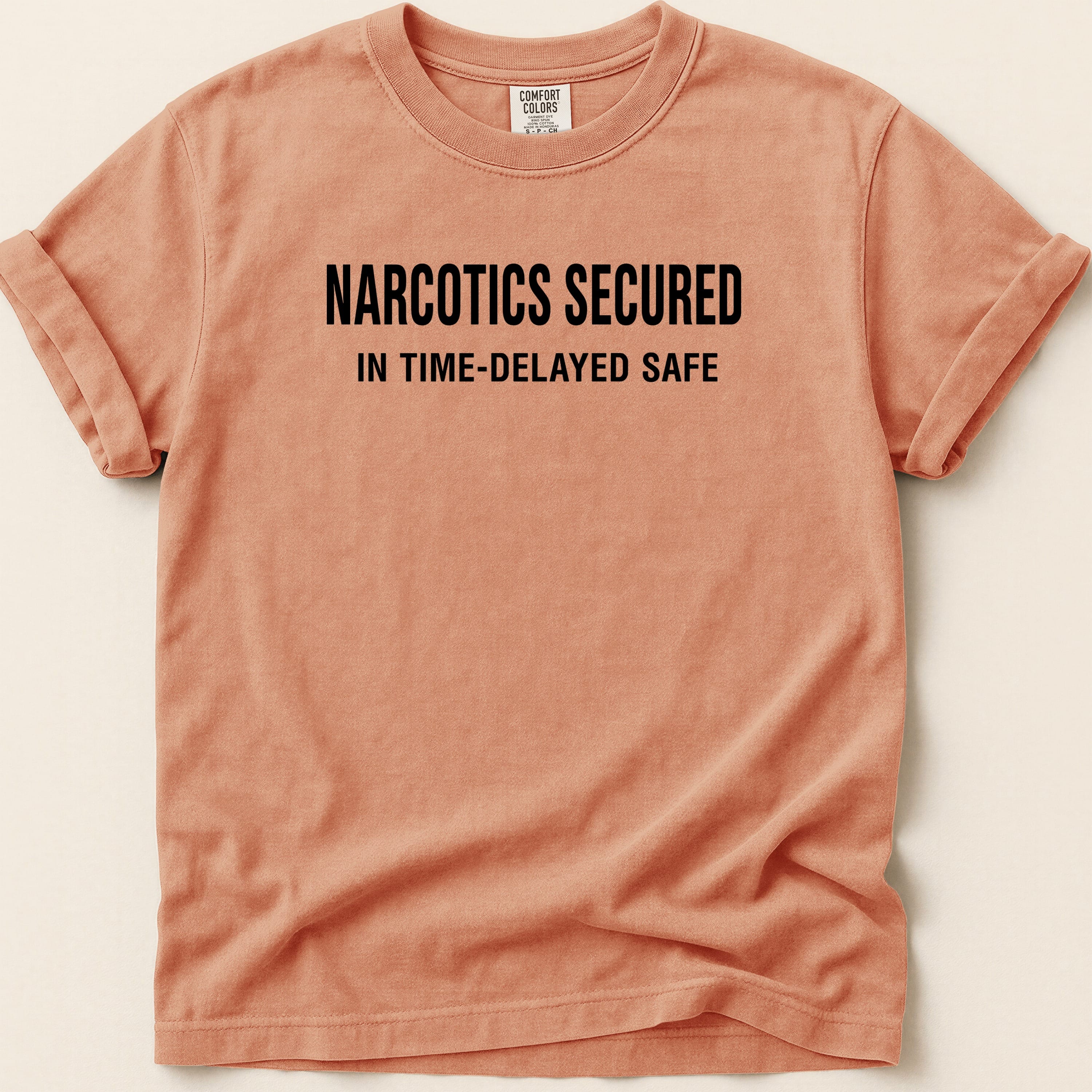 Peach t-shirt with "NARCOTICS SECURED IN TIME-DELAYED SAFE" text.