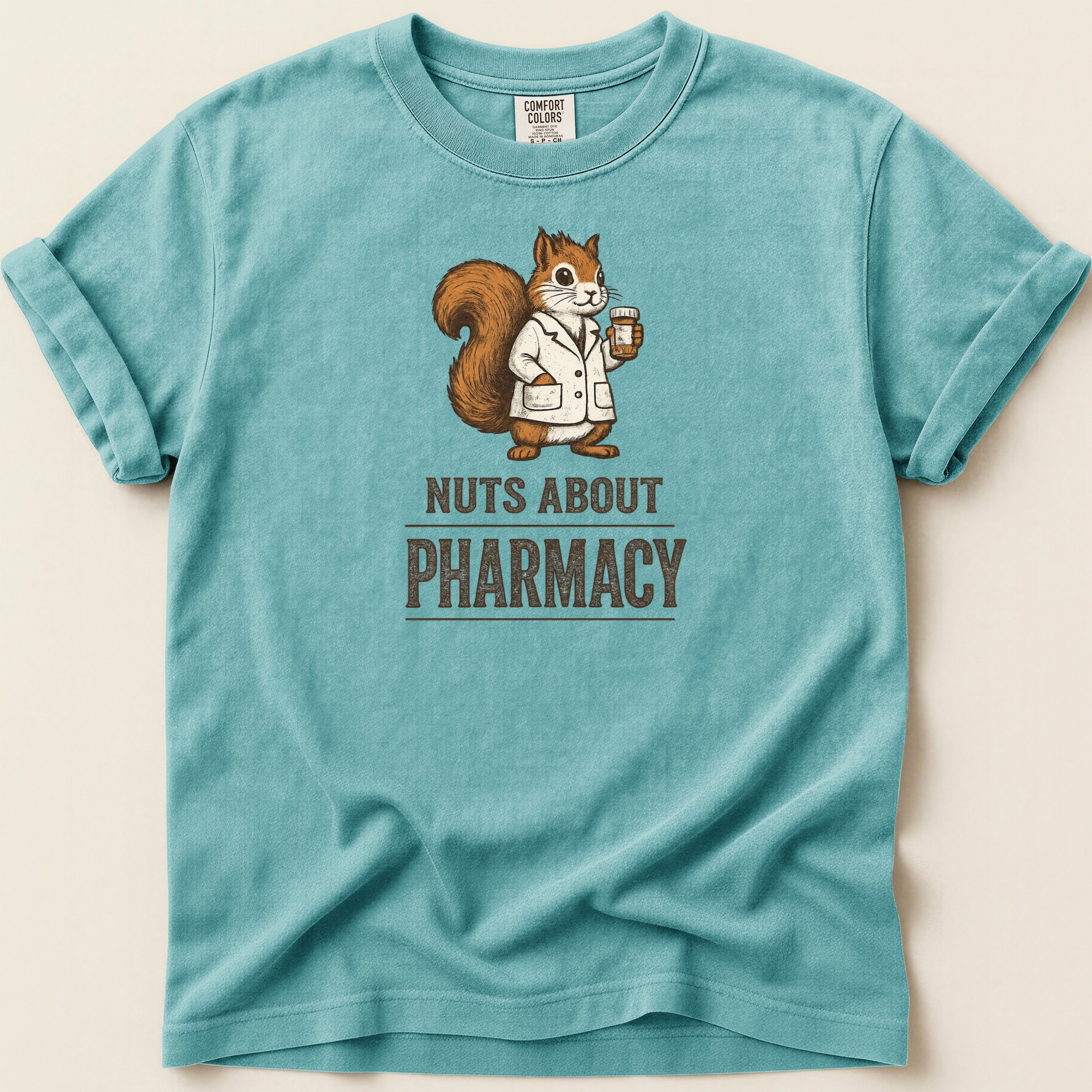 Teal t-shirt with a squirrel in a lab coat holding a prescription bottle and the text "Nuts About Pharmacy".