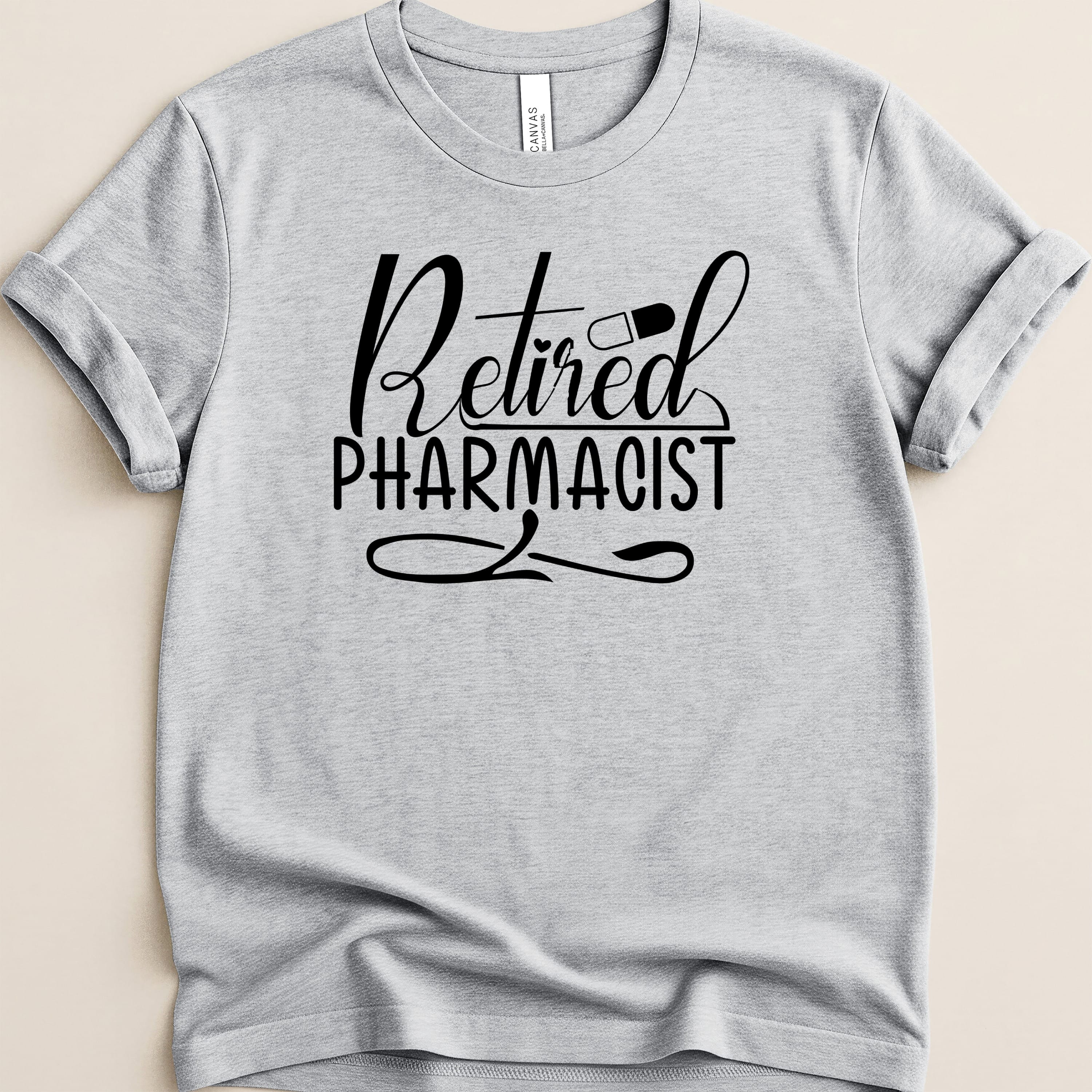 Grey t-shirt with "Retired Pharmacist" text and a capsule graphic.