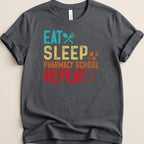 Dark t-shirt with "Eat Sleep Pharmacy School Repeat" text and icons.