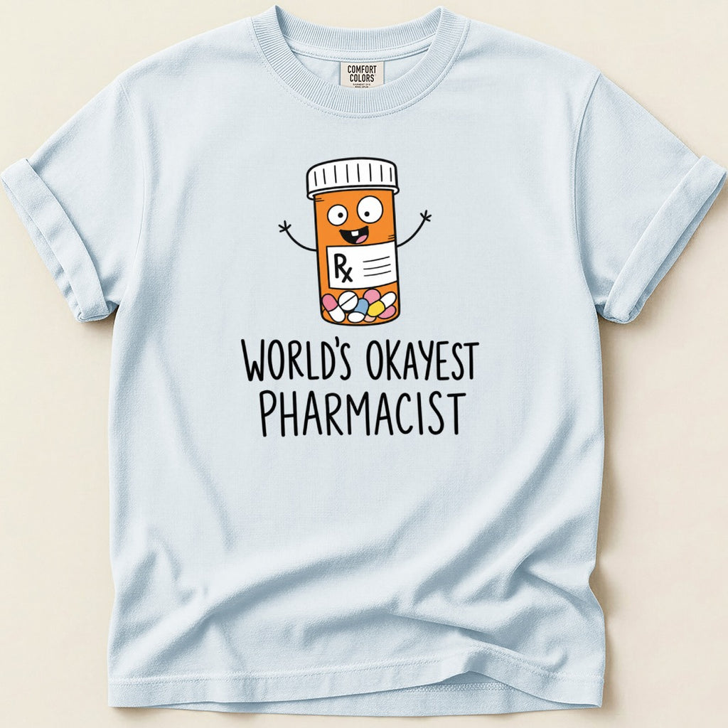 Light blue t-shirt with cartoon pill bottle and text "WORLD'S OKAYEST PHARMACIST".