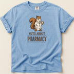 Light blue t-shirt with a squirrel in a lab coat holding a cup, text reads "Nuts About Pharmacy".