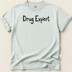 Light blue t-shirt with black speckled text reading "Drug Expert".