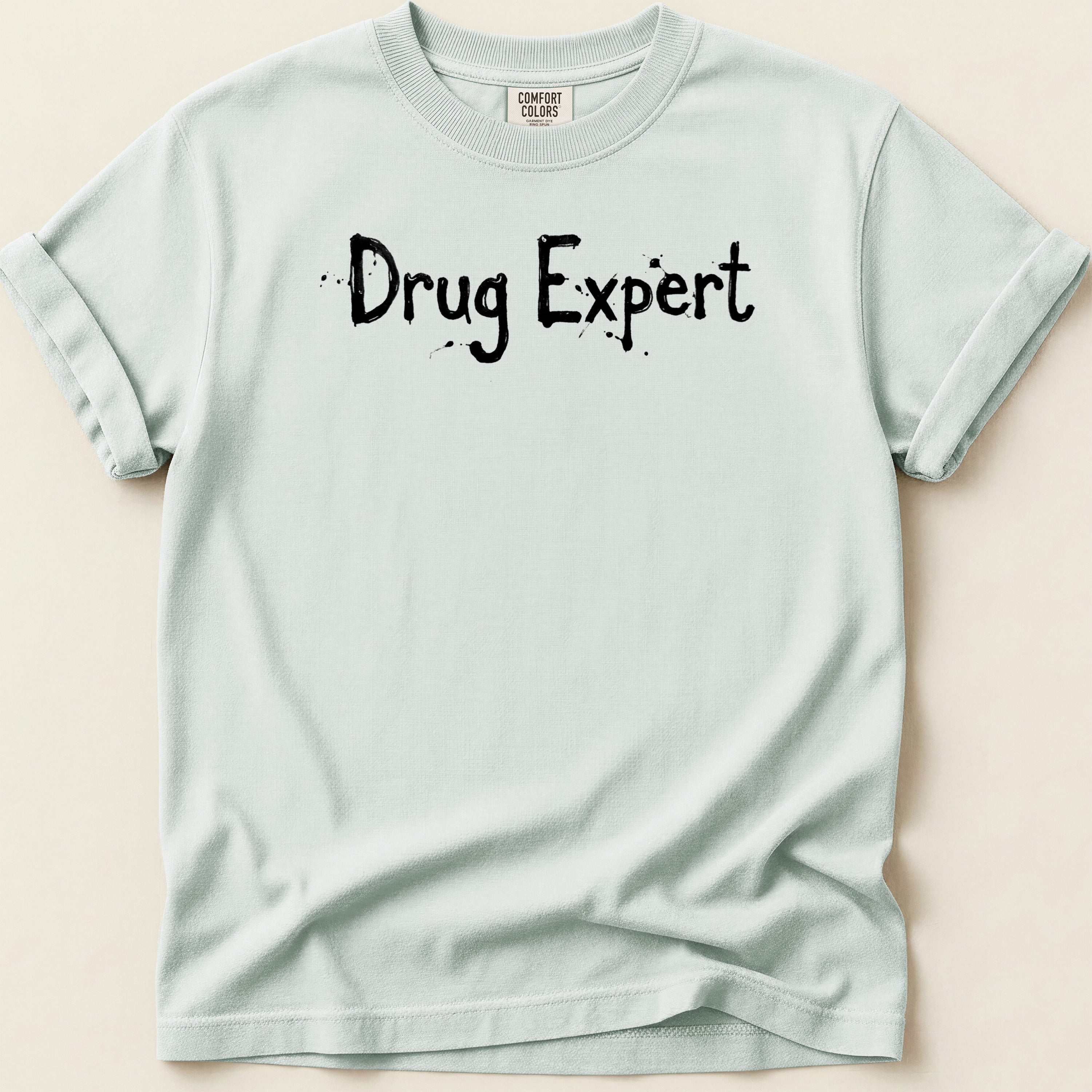 Light blue t-shirt with black speckled text reading "Drug Expert".