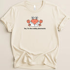 Cream t-shirt with a cartoon crab wearing glasses and a lab coat with text "Yes, I'm the crabby pharmacist."