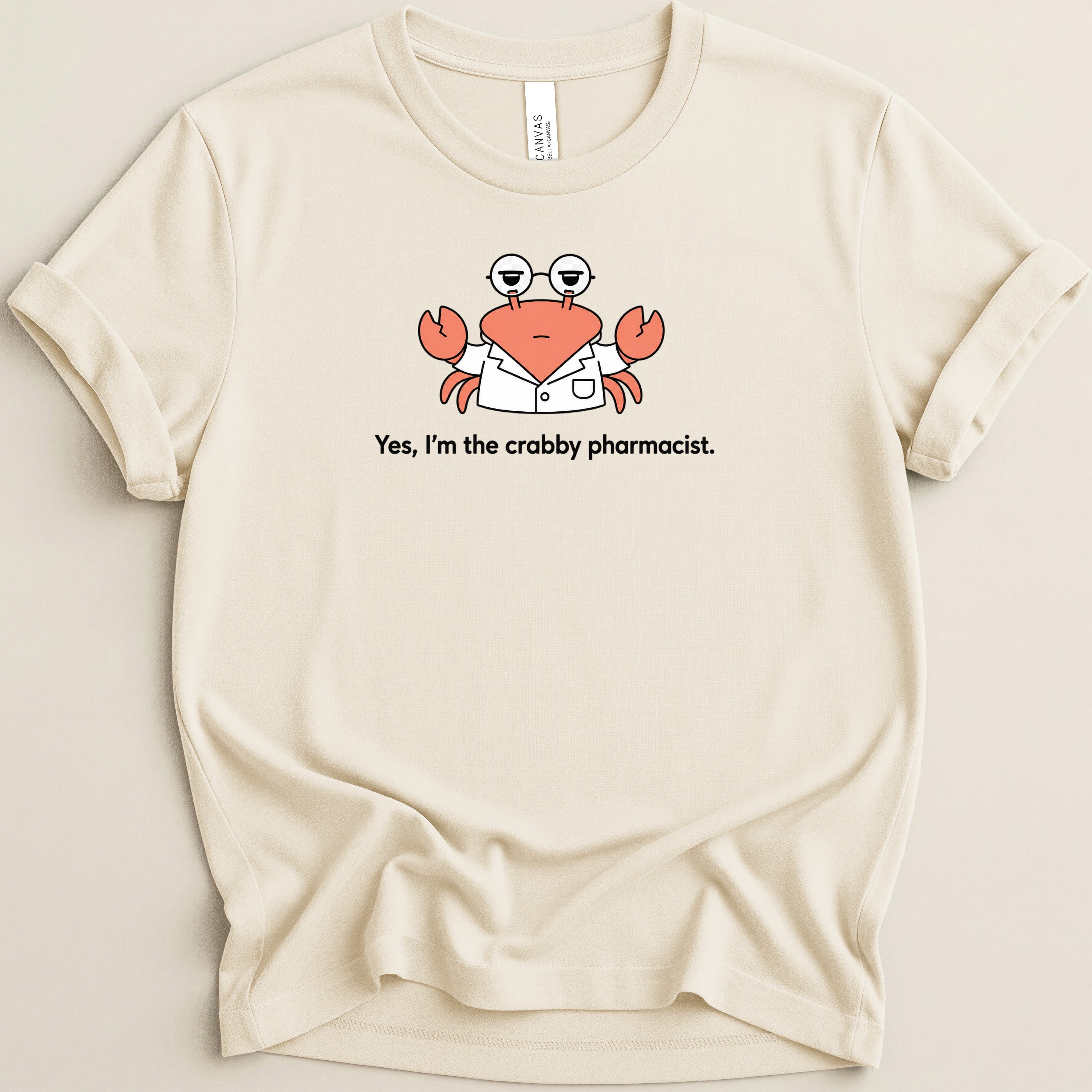 Cream t-shirt with a cartoon crab wearing glasses and a lab coat with text "Yes, I'm the crabby pharmacist."