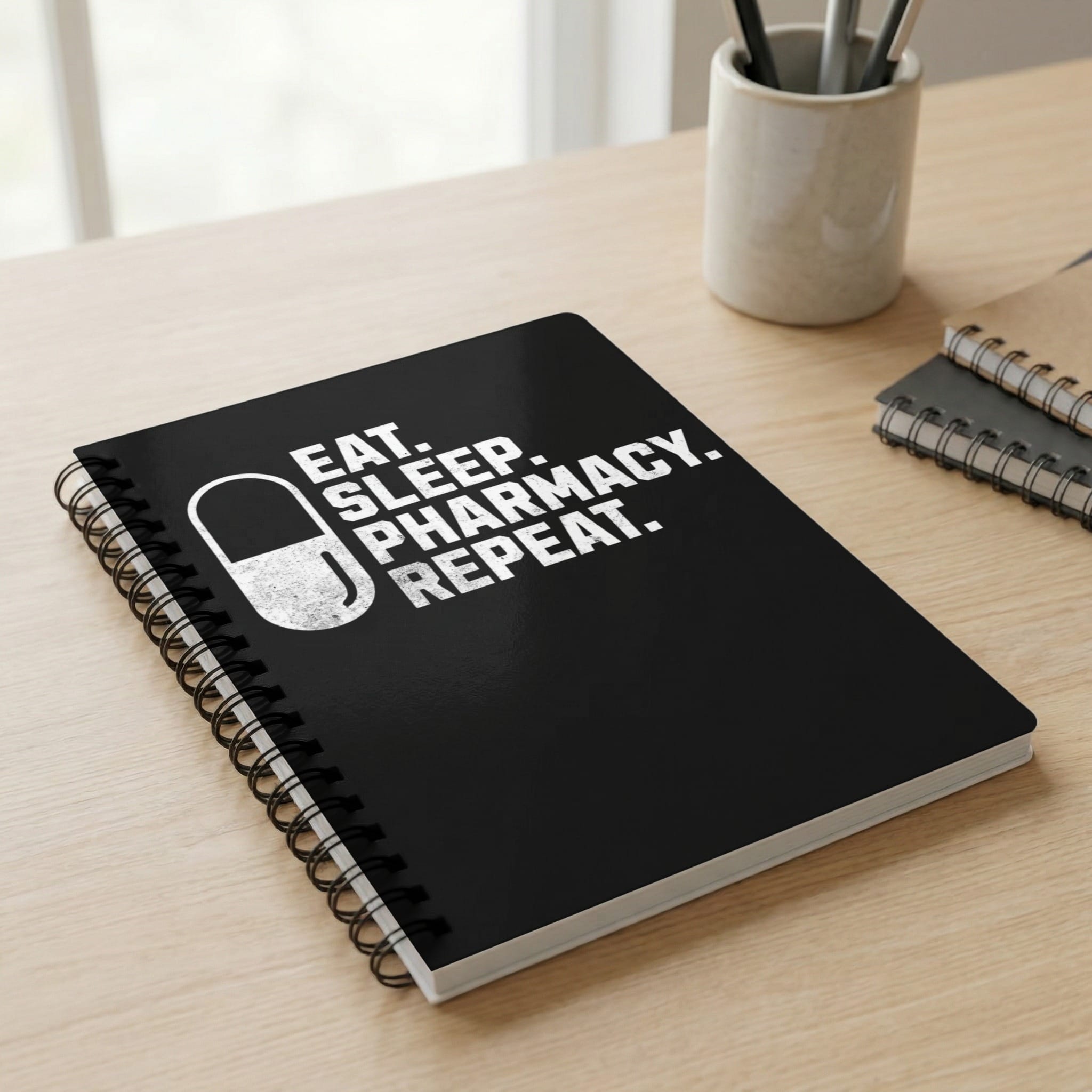 Black spiral notebook with "EAT. SLEEP. PHARMACY. REPEAT." text.