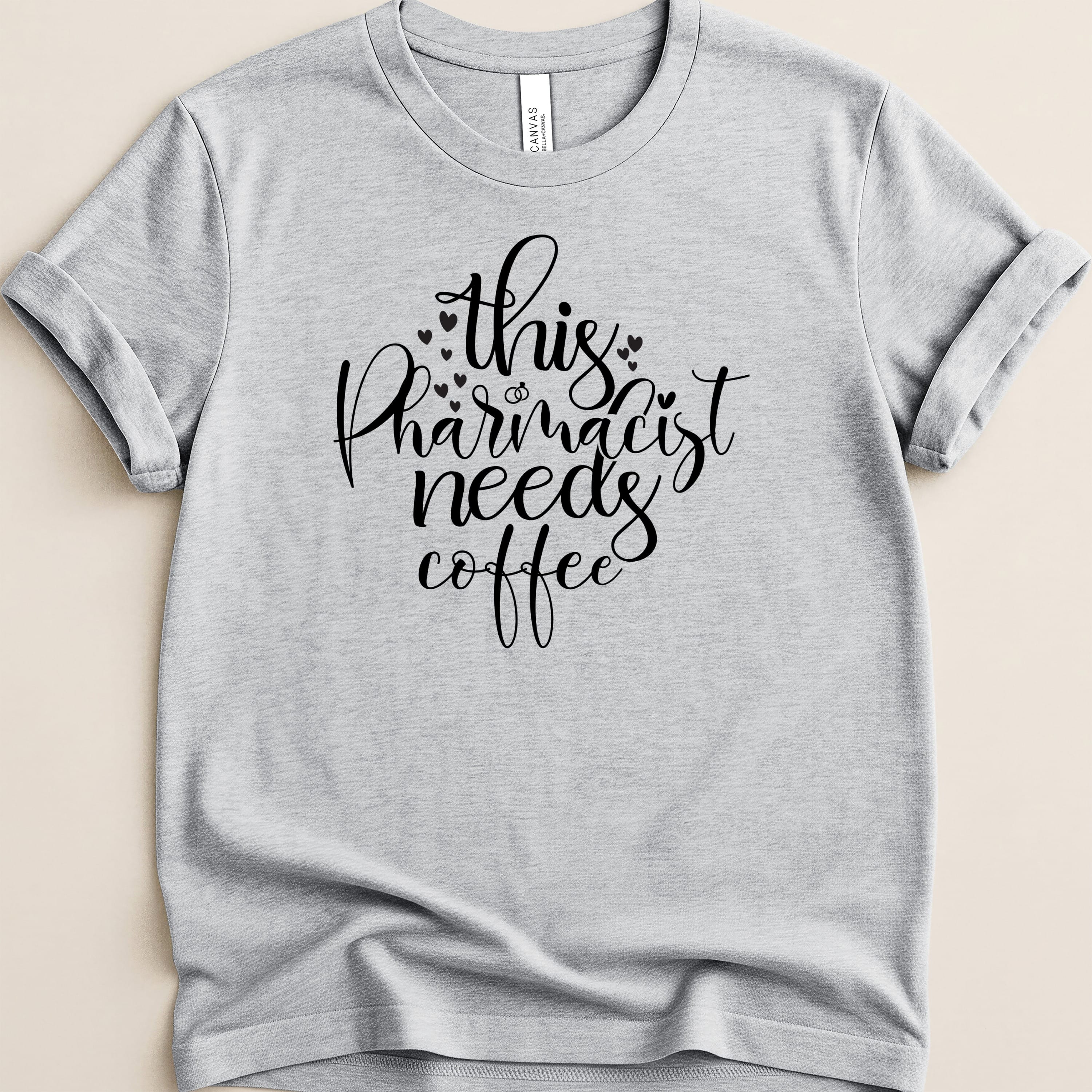 Light grey t-shirt with "this pharmacist needs coffee" text and heart details.