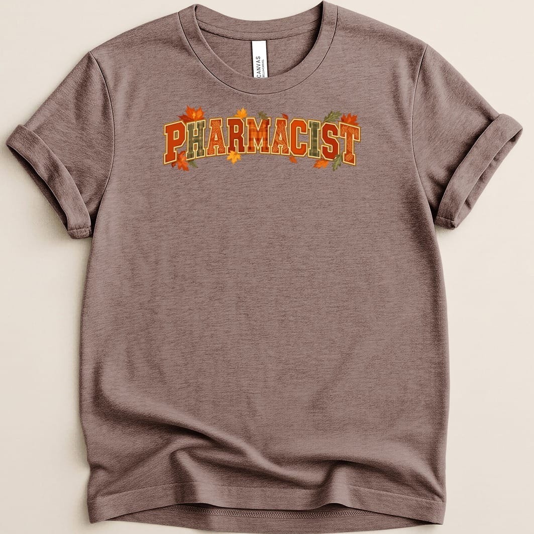 Brown crewneck t-shirt with rolled sleeves featuring the word PHARMACIST in orange and autumn leaf graphics.