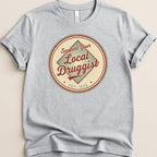 T-shirt with "Support Your Local Druggist EST. 1920" circular logo.