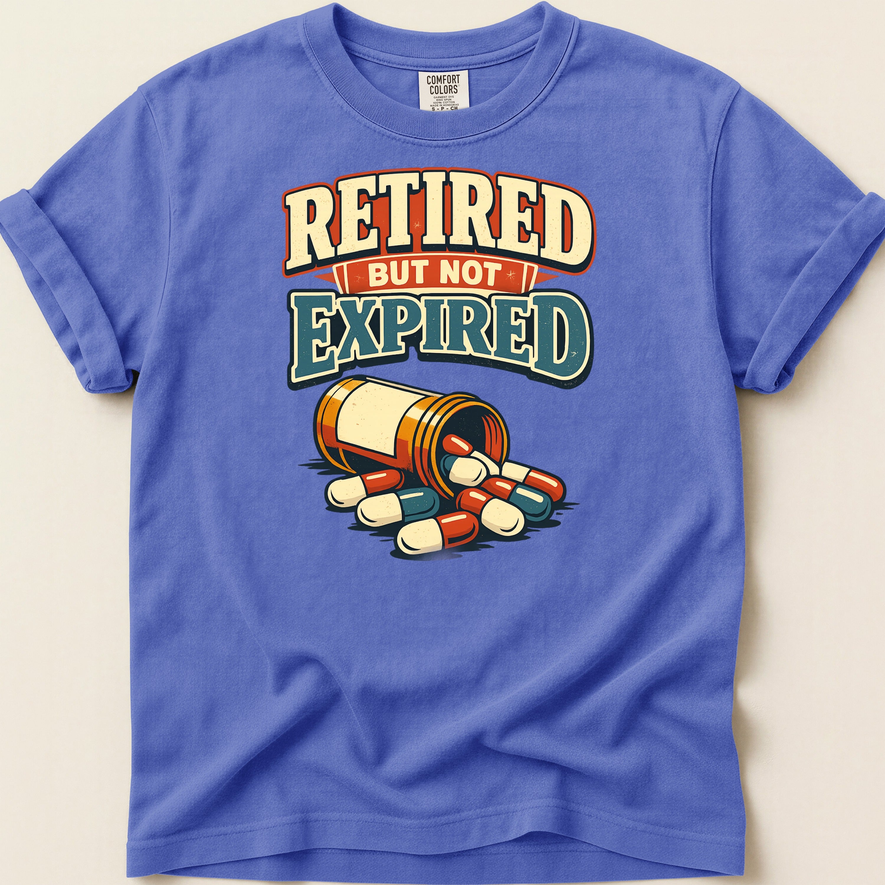T-shirt with text "Retired But Not Expired" and spilled pill bottle.
