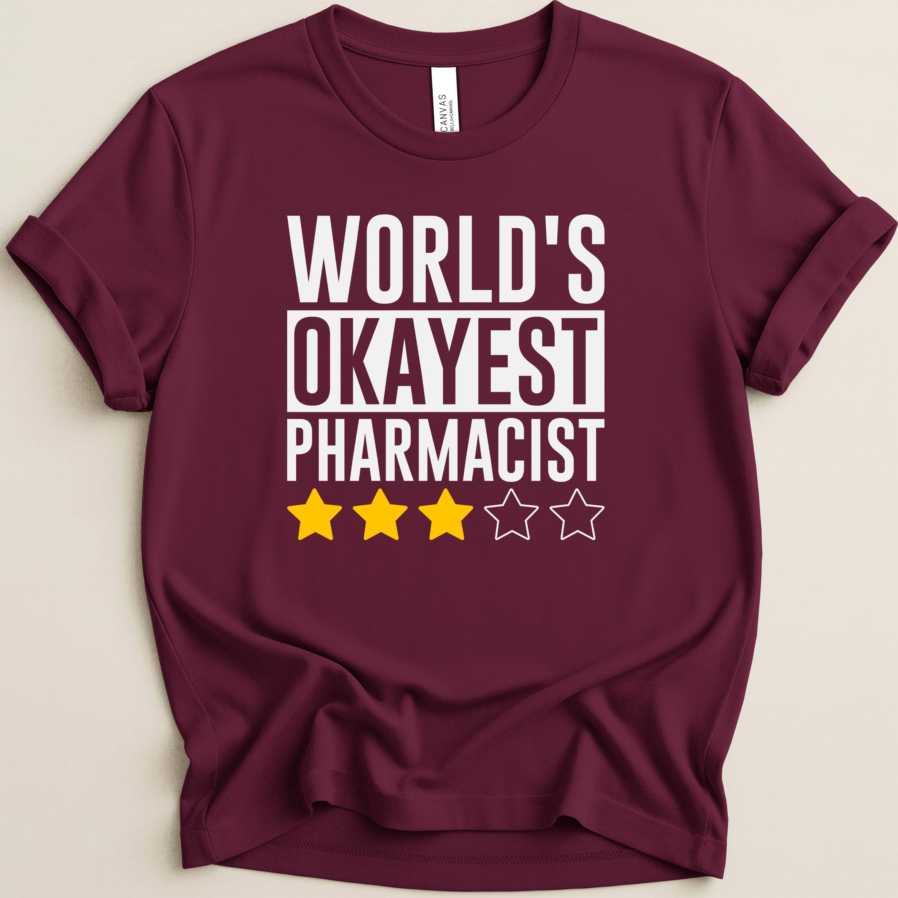 Maroon t-shirt with "WORLD'S OKAYEST PHARMACIST" and three stars.