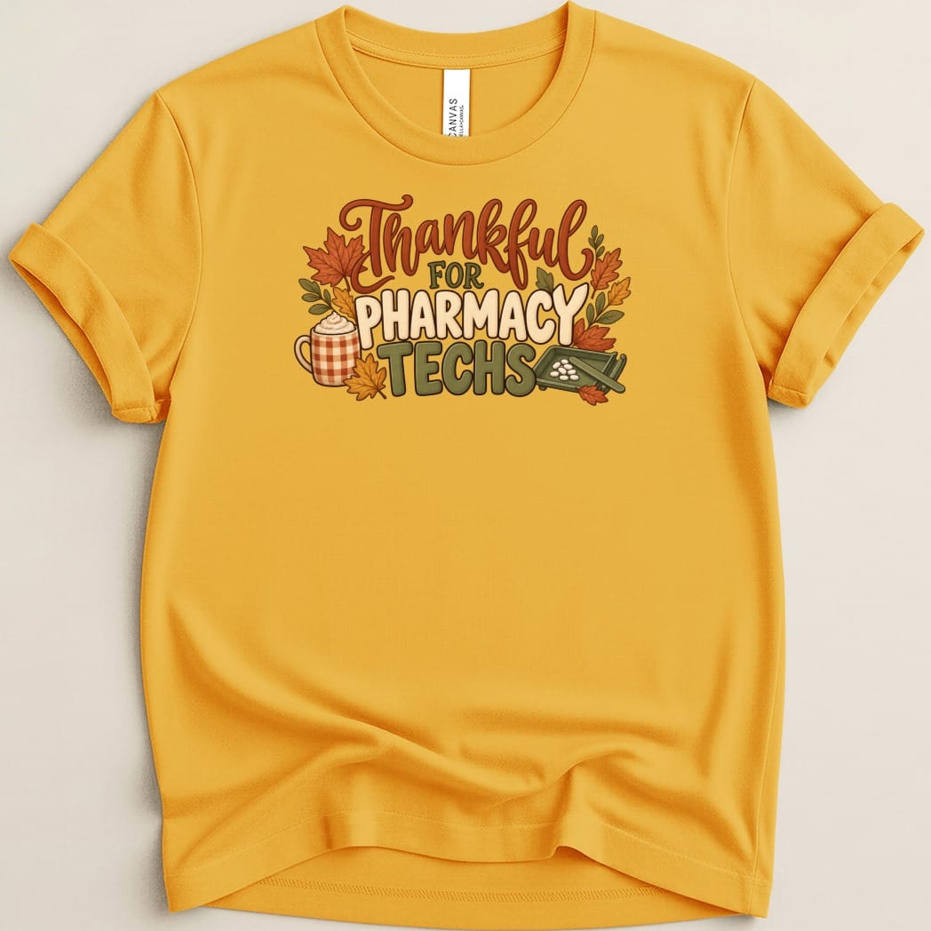 Gold crewneck t-shirt with rolled sleeves featuring the text Thankful for Pharmacy Techs, autumn leaves, a coffee mug, and a pill counting tray.
