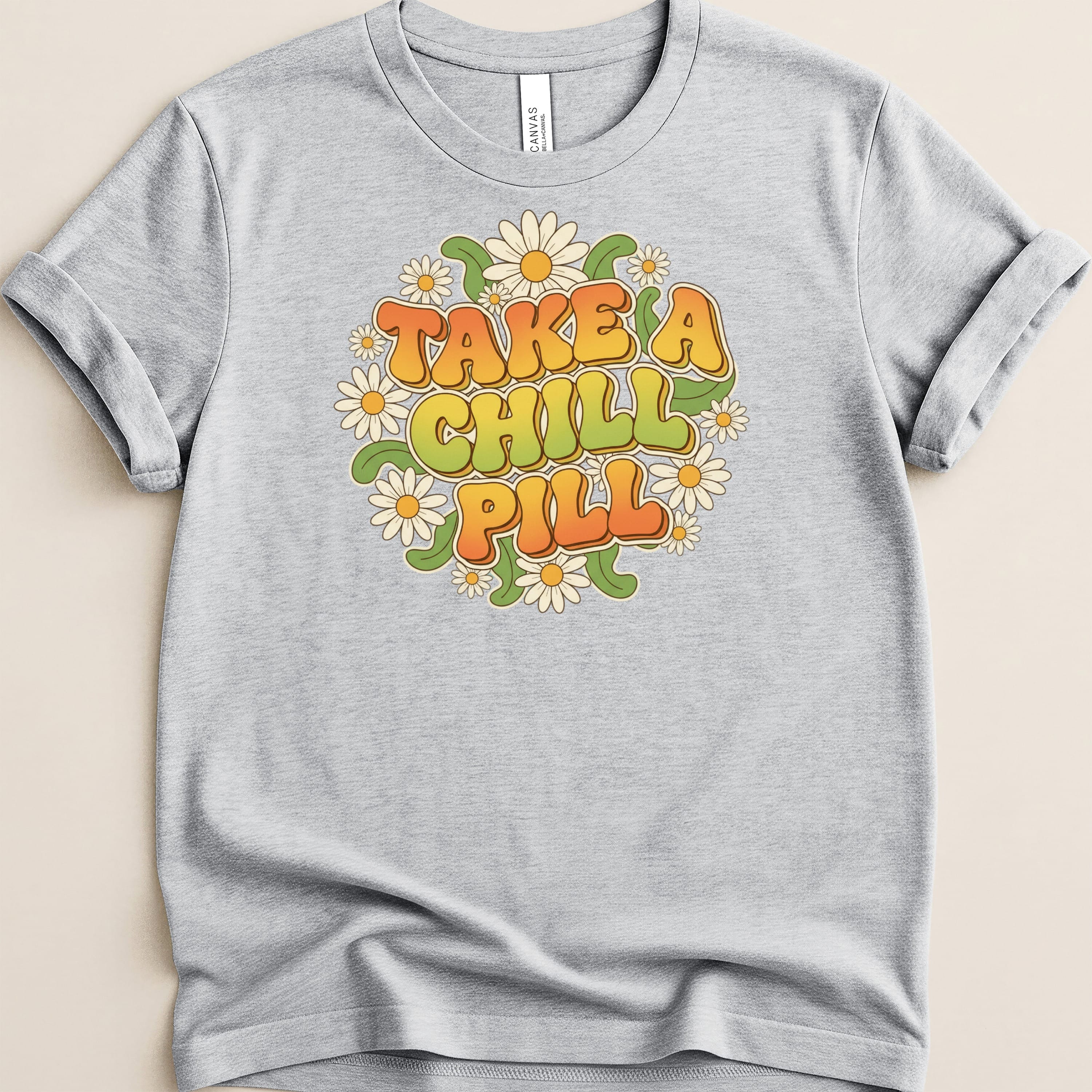 Grey t-shirt with "TAKE A CHILL PILL" in retro font surrounded by daisies.