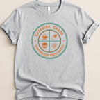 Grey t-shirt with circular graphic reading "CAFFEINE, CHAOS CONTROLLED SUBSTANCES" and icons.