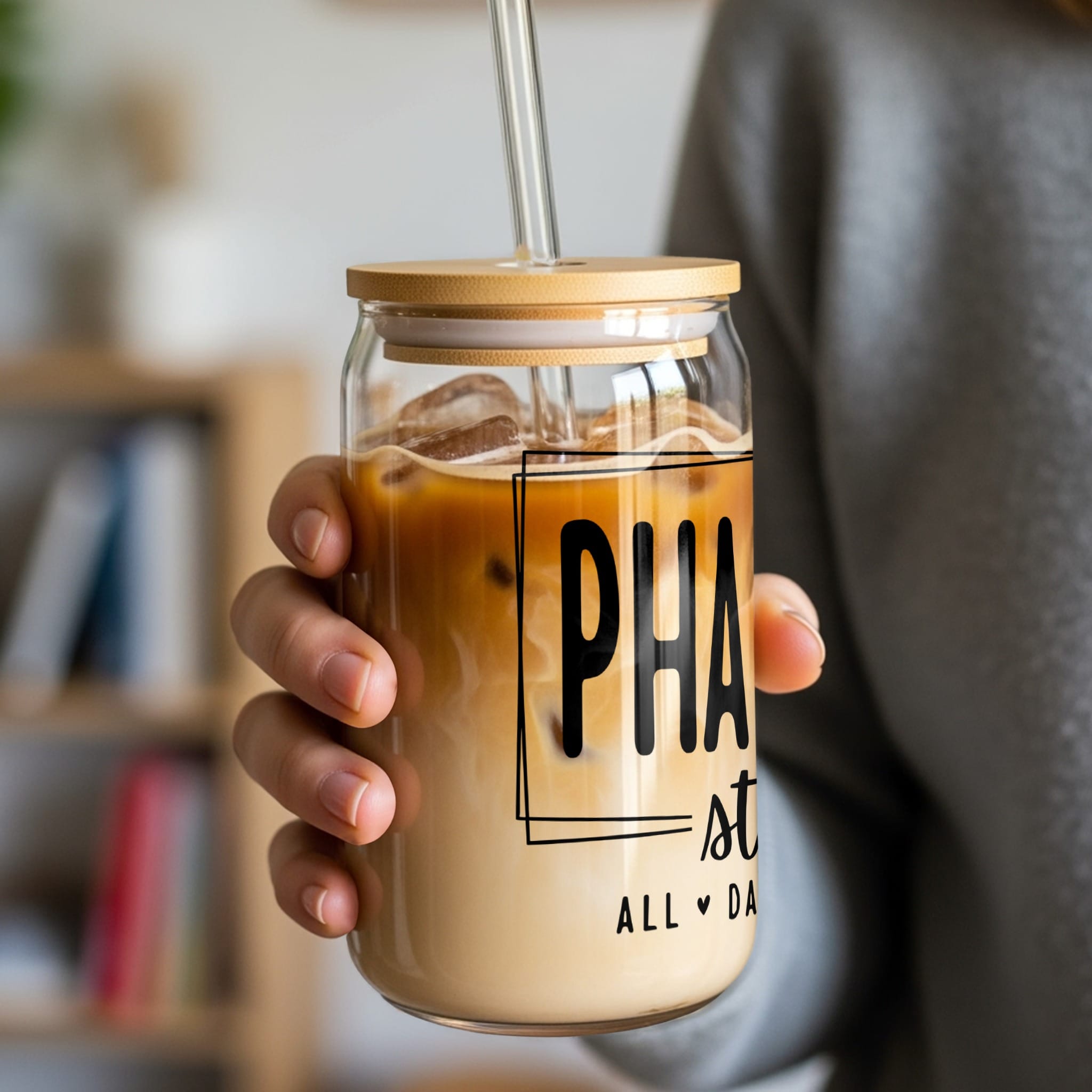 Glass tumbler with "PHA st ALL DAY" text and iced coffee.
