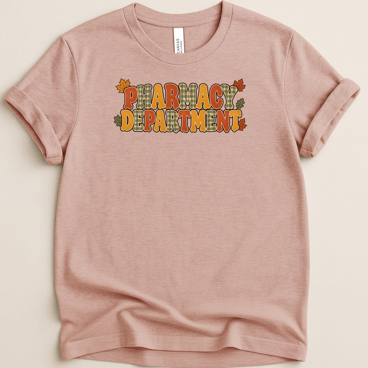 Dusty pink crewneck t-shirt featuring the retro text Pharmacy Department decorated with autumn leaves and plaid.