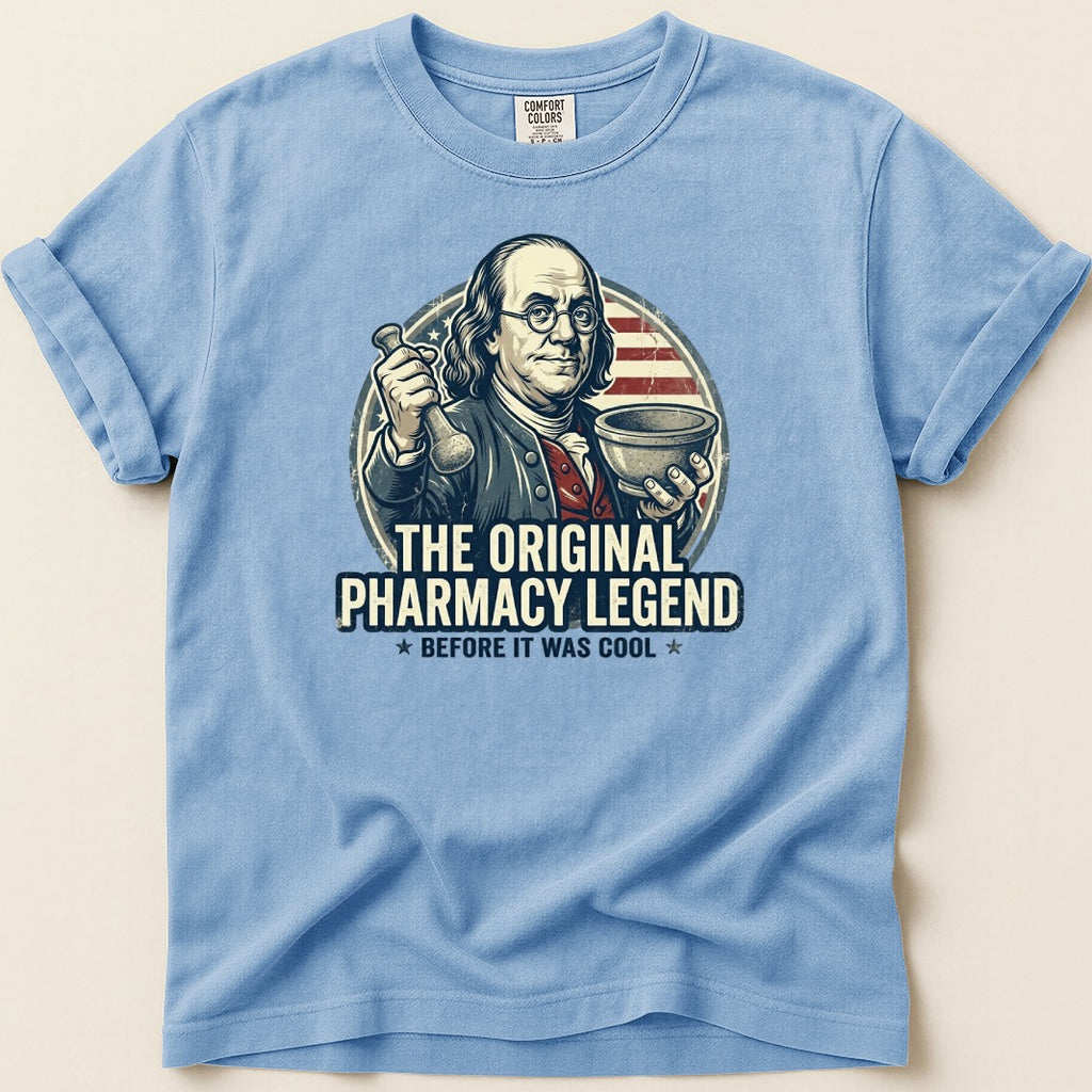 Blue t-shirt with Benjamin Franklin holding pharmacy tools, "The Original Pharmacy Legend" text.
