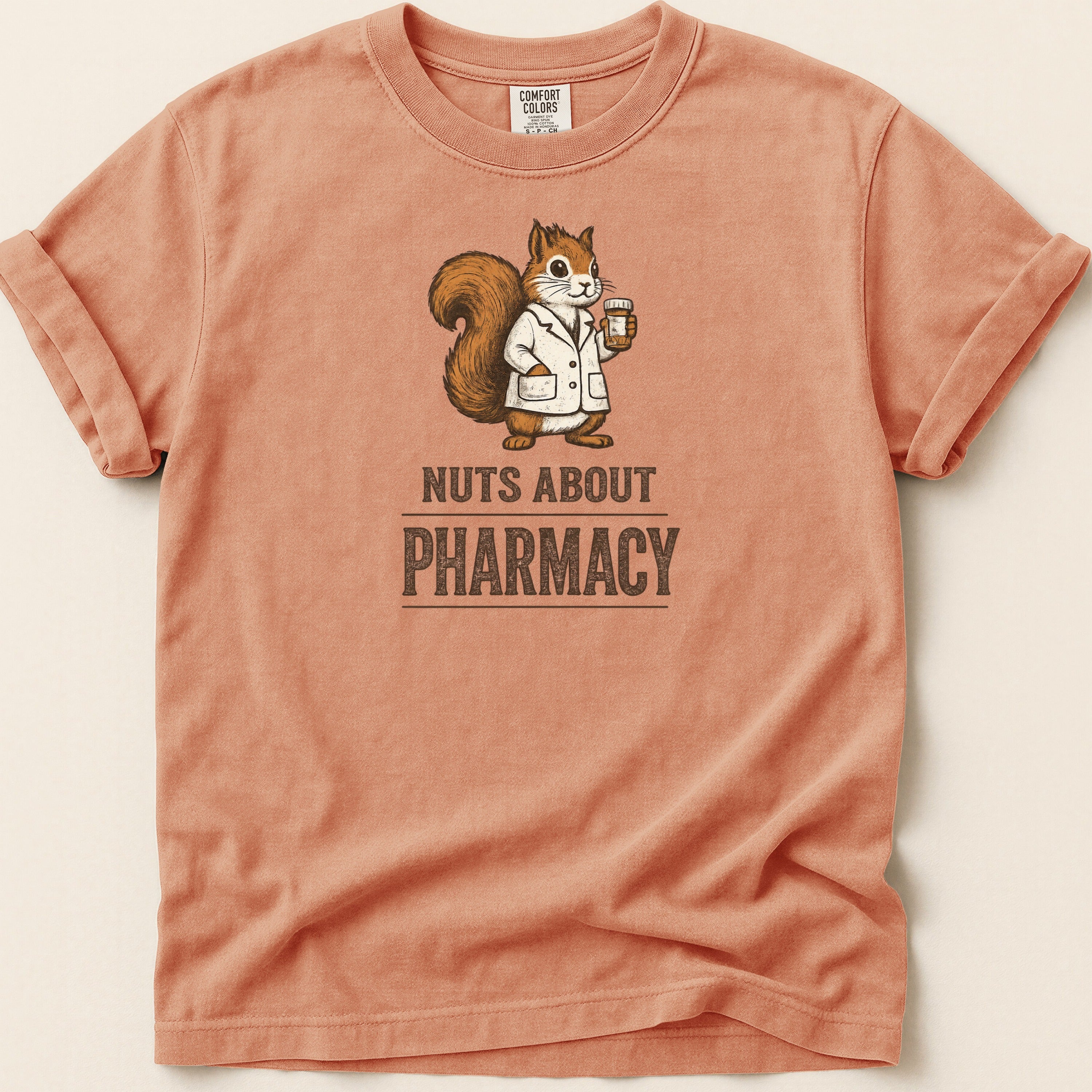 Orange shirt with a squirrel wearing a lab coat and holding medicine, text "NUTS ABOUT PHARMACY".