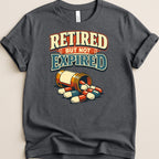 T-shirt with text "Retired but not expired" and a bottle of pills.