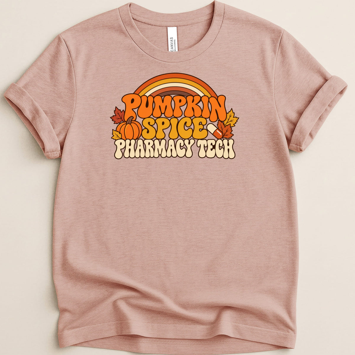 A mauve t-shirt with a retro-style graphic that reads Pumpkin Spice Pharmacy Tech, featuring a pumpkin, pill, and autumn leaves.
