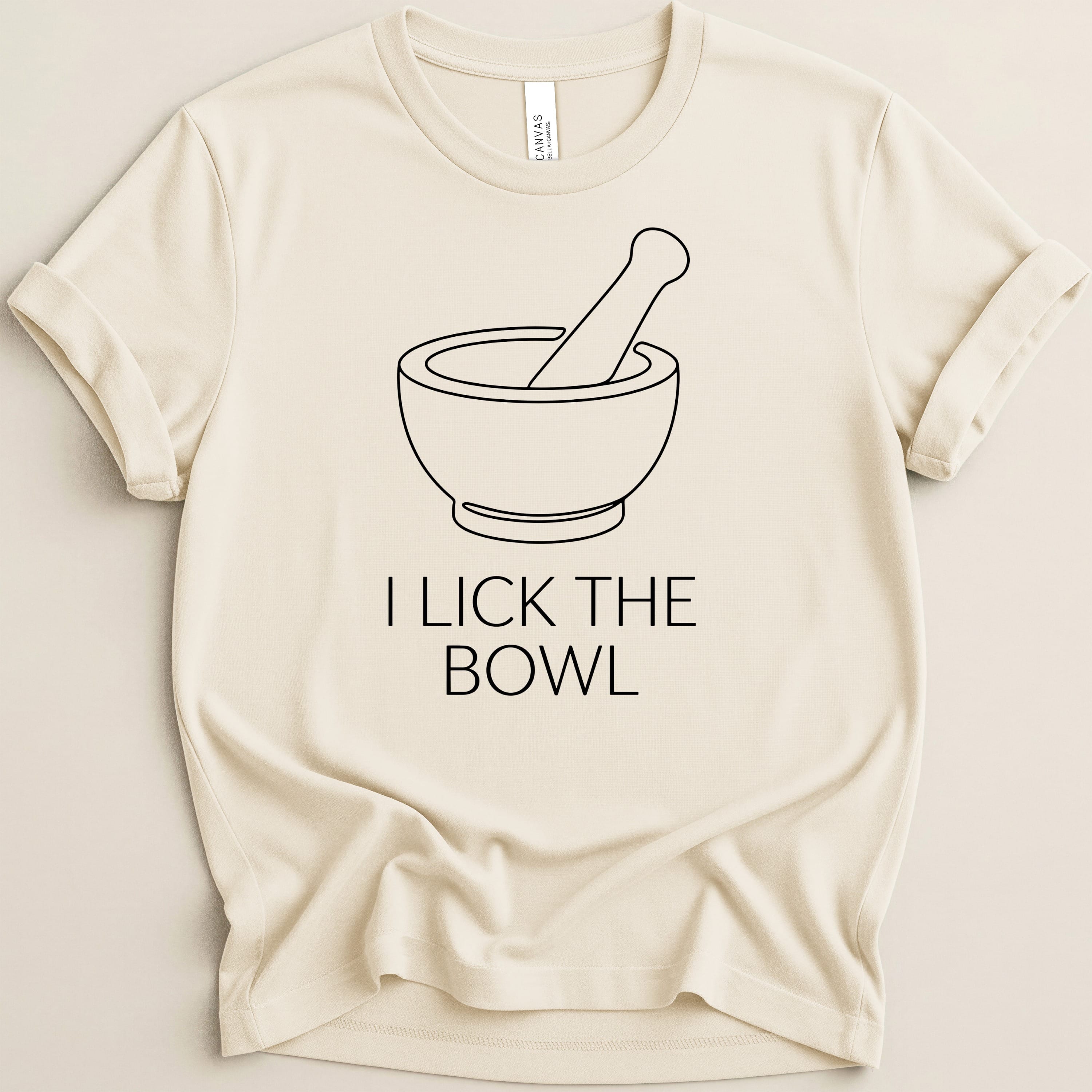 Cream t-shirt with black outline of a mortar and pestle and text "I LICK THE BOWL".