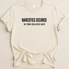 Cream t-shirt with black text: NARCOTICS SECURED IN TIME-DELAYED SAFE