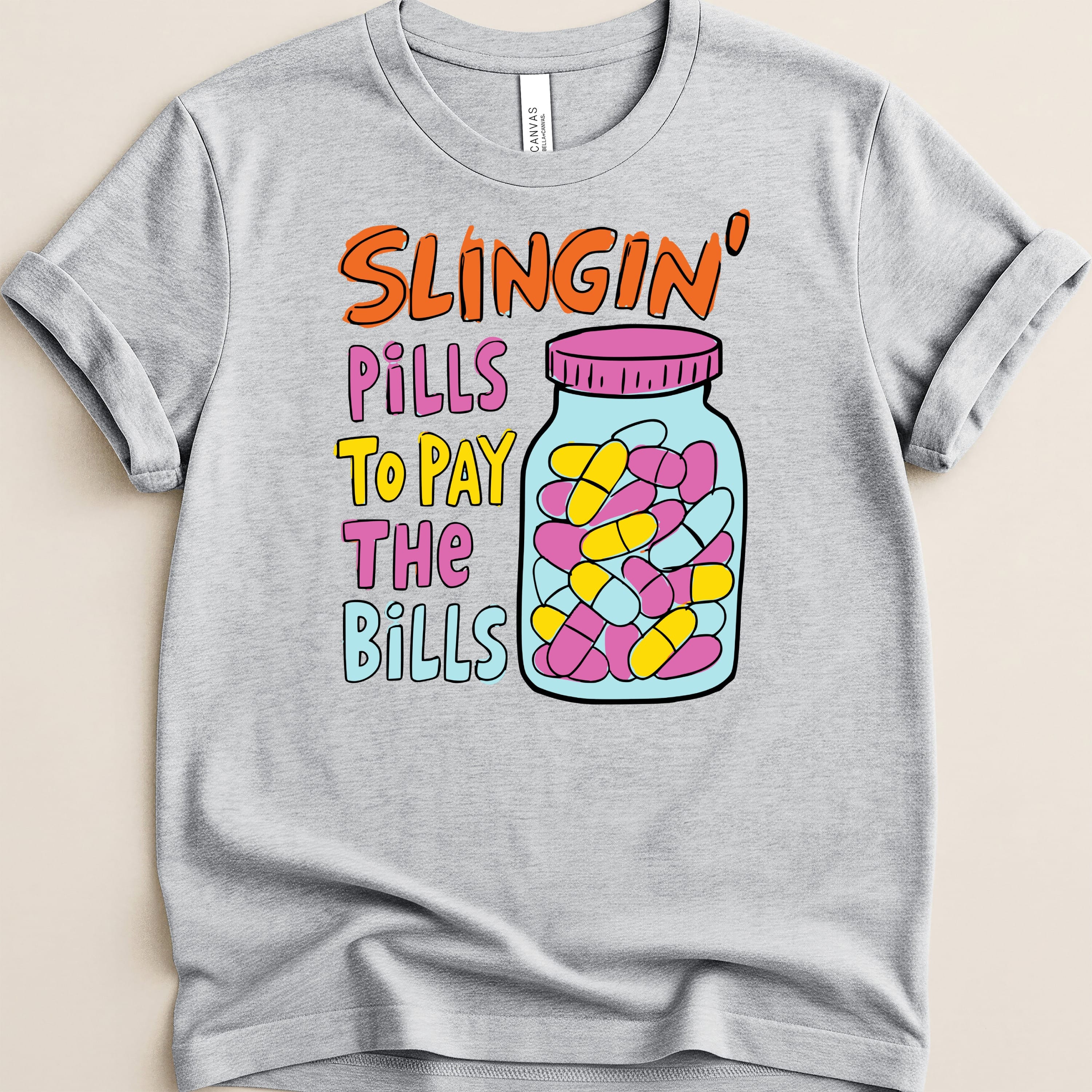 Grey t-shirt with multicolor text and a jar of pills graphic.