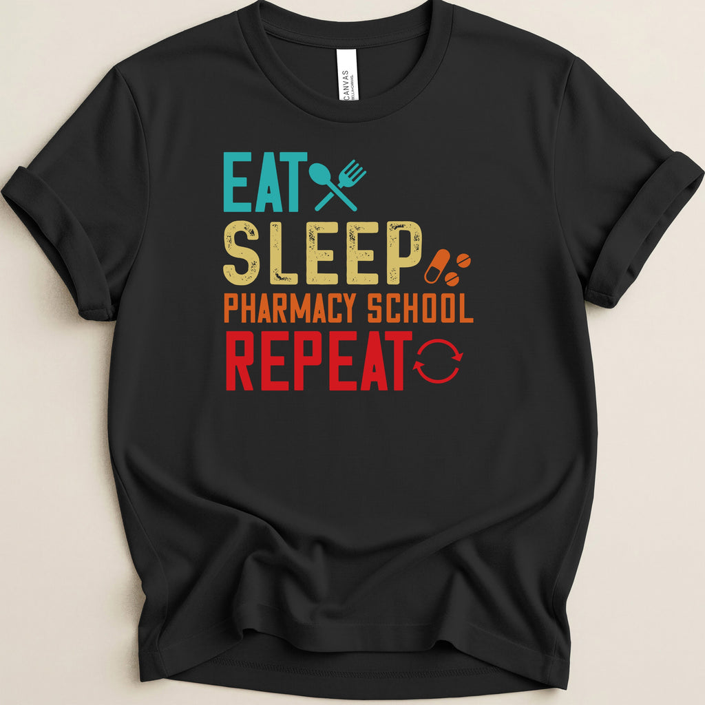 Black t-shirt with "Eat Sleep Pharmacy School Repeat" text in colorful block letters.
