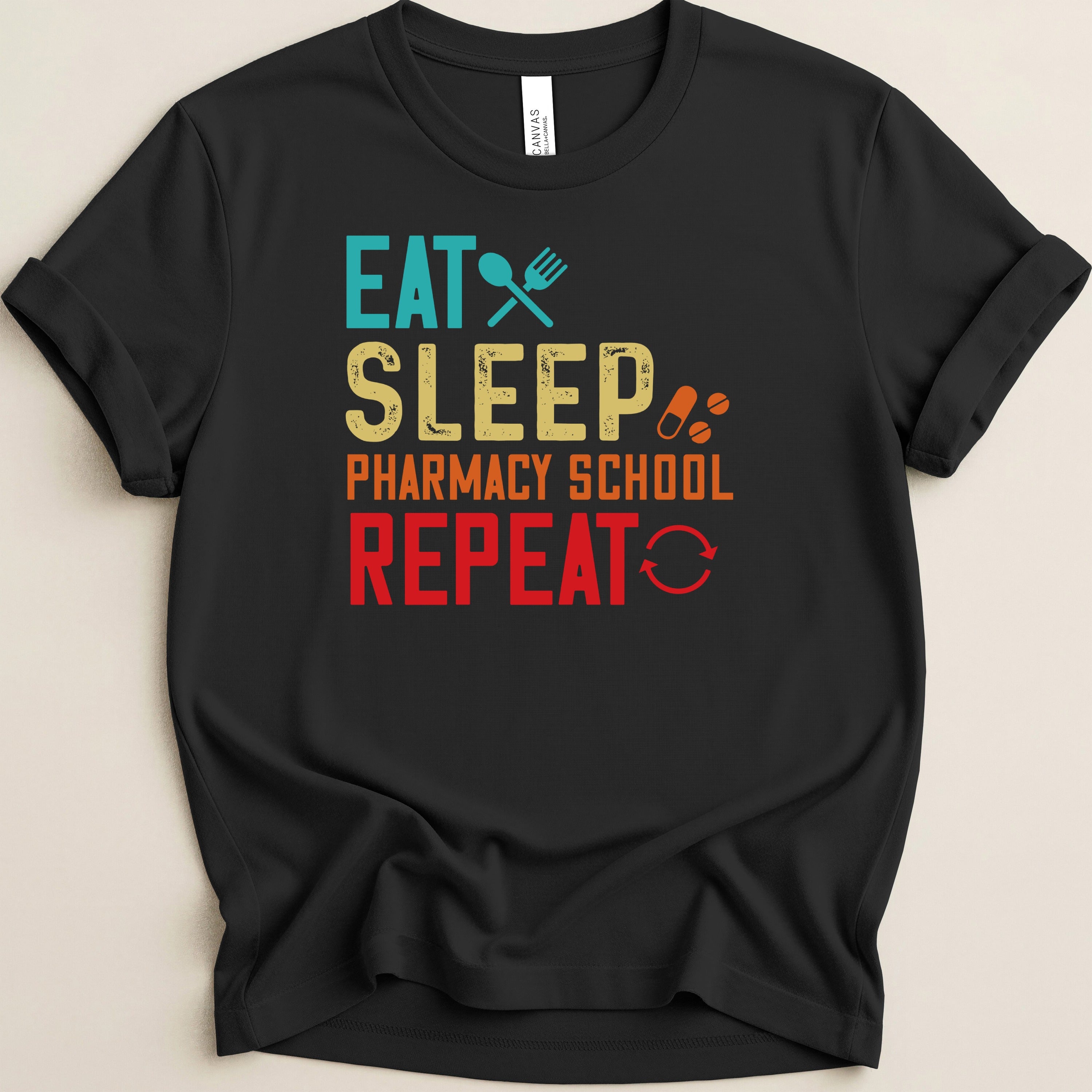 Black t-shirt with "Eat Sleep Pharmacy School Repeat" text in colorful block letters.