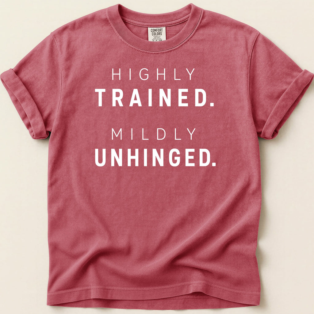 Red t-shirt with "HIGHLY TRAINED. MILDLY UNHINGED." printed in white text.