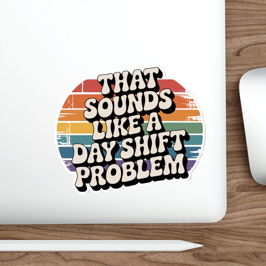 Sticker with "THAT SOUNDS LIKE A DAY SHIFT PROBLEM" text and rainbow stripes.